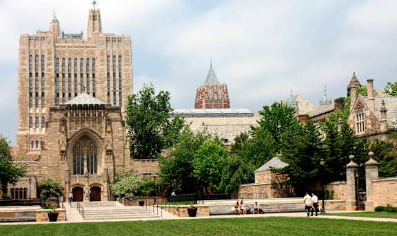 A large, historic building with a green lawn in front.